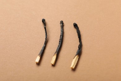 Photo of Burnt matches on beige background, closeup view
