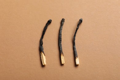 Photo of Burnt matches on beige background, closeup view