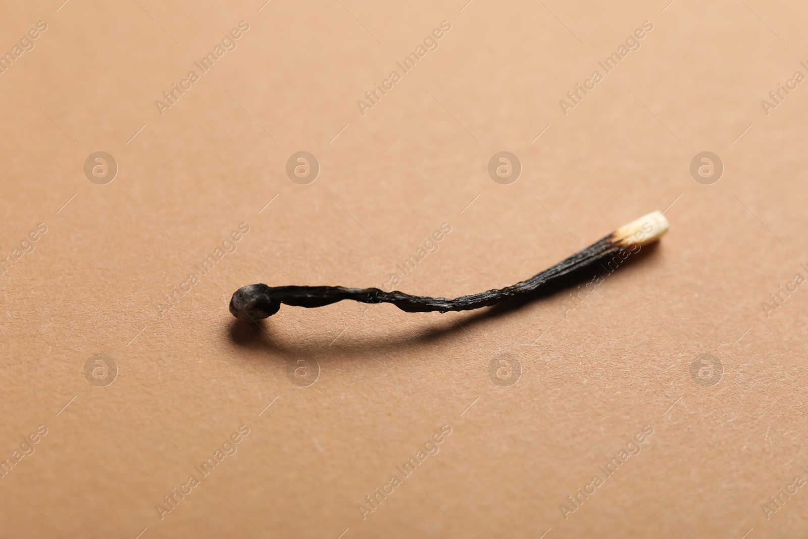 One burnt match on beige background, closeup Photo of One burnt match on beige background, closeup