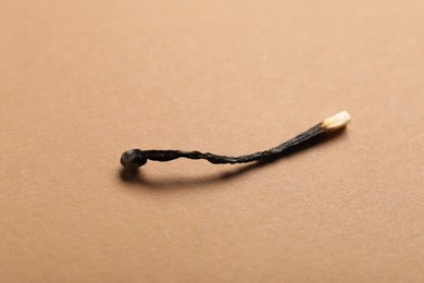 Photo of One burnt match on beige background, closeup