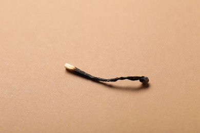 Photo of One burnt match on beige background, closeup