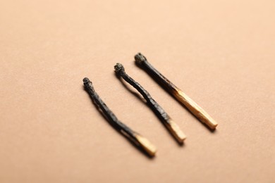 Photo of Burnt matches on beige background, closeup view