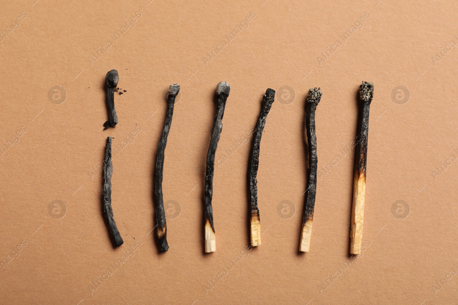 Burnt matches on beige background, flat lay Photo of Burnt matches on beige background, flat lay