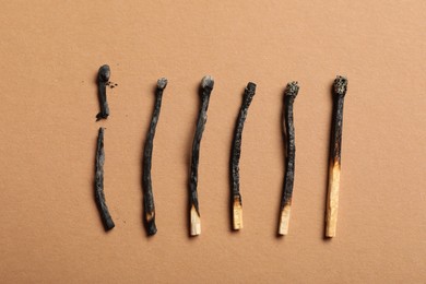 Photo of Burnt matches on beige background, flat lay