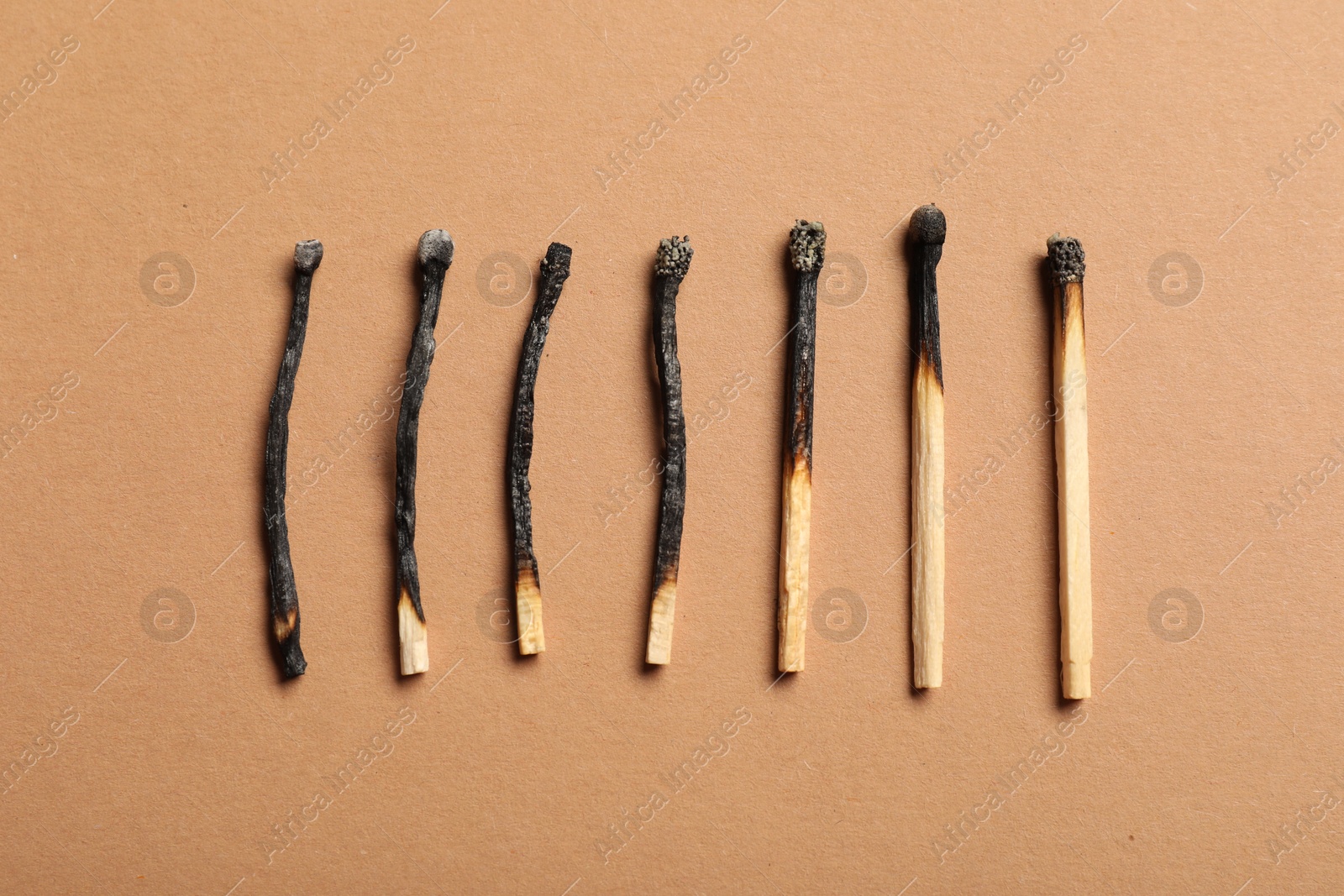 Burnt matches on beige background, flat lay Photo of Burnt matches on beige background, flat lay