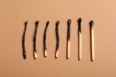 Photo of Burnt matches on beige background, flat lay
