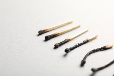 Photo of Burnt matches on light grey background, closeup