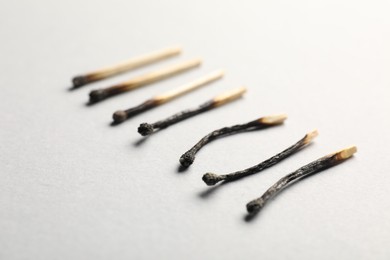 Photo of Burnt matches on light grey background, closeup