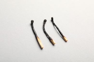 Photo of Burnt matches on light grey background, closeup