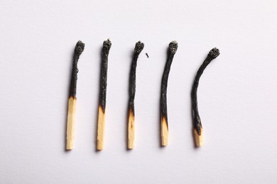 Photo of Burnt matches on light grey background, flat lay