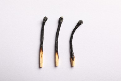 Photo of Burnt matches on light grey background, flat lay
