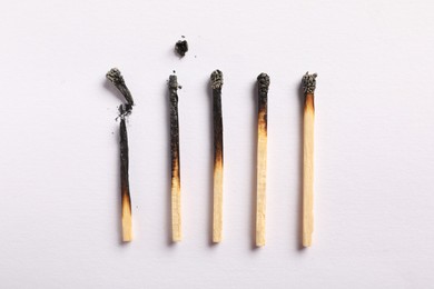 Photo of Burnt matches on light grey background, flat lay