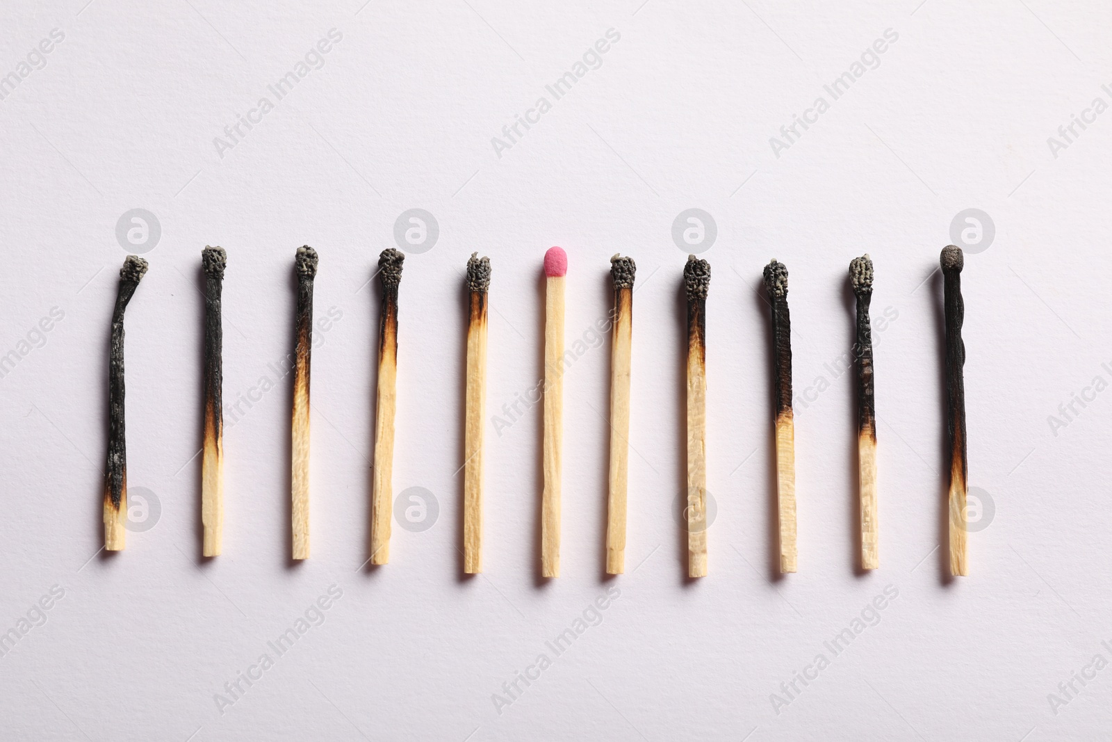 Burnt and whole matches on light grey background, flat lay Photo of Burnt and whole matches on light grey background, flat lay