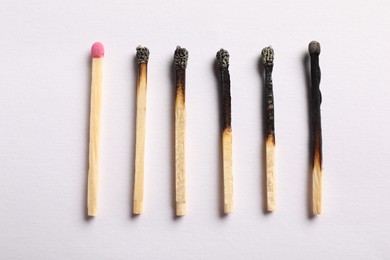 Photo of Burnt and whole matches on light grey background, flat lay