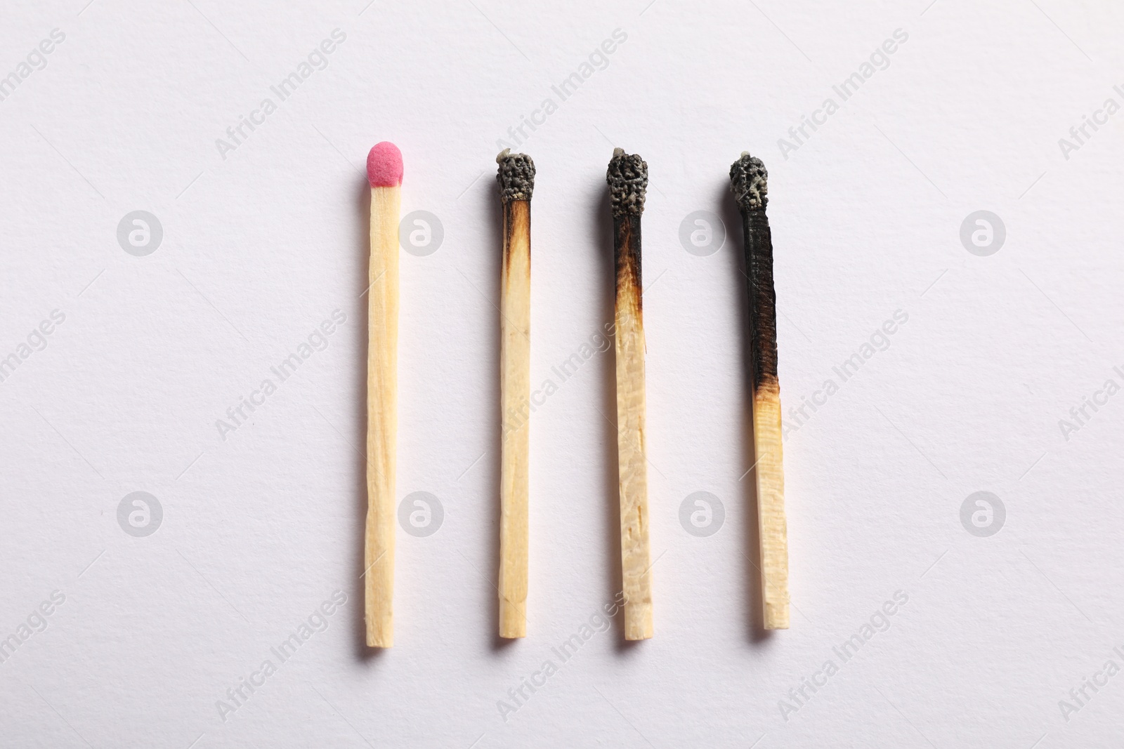 Photo of Burnt and whole matches on light grey background, flat lay