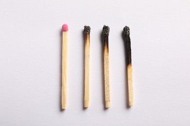 Photo of Burnt and whole matches on light grey background, flat lay