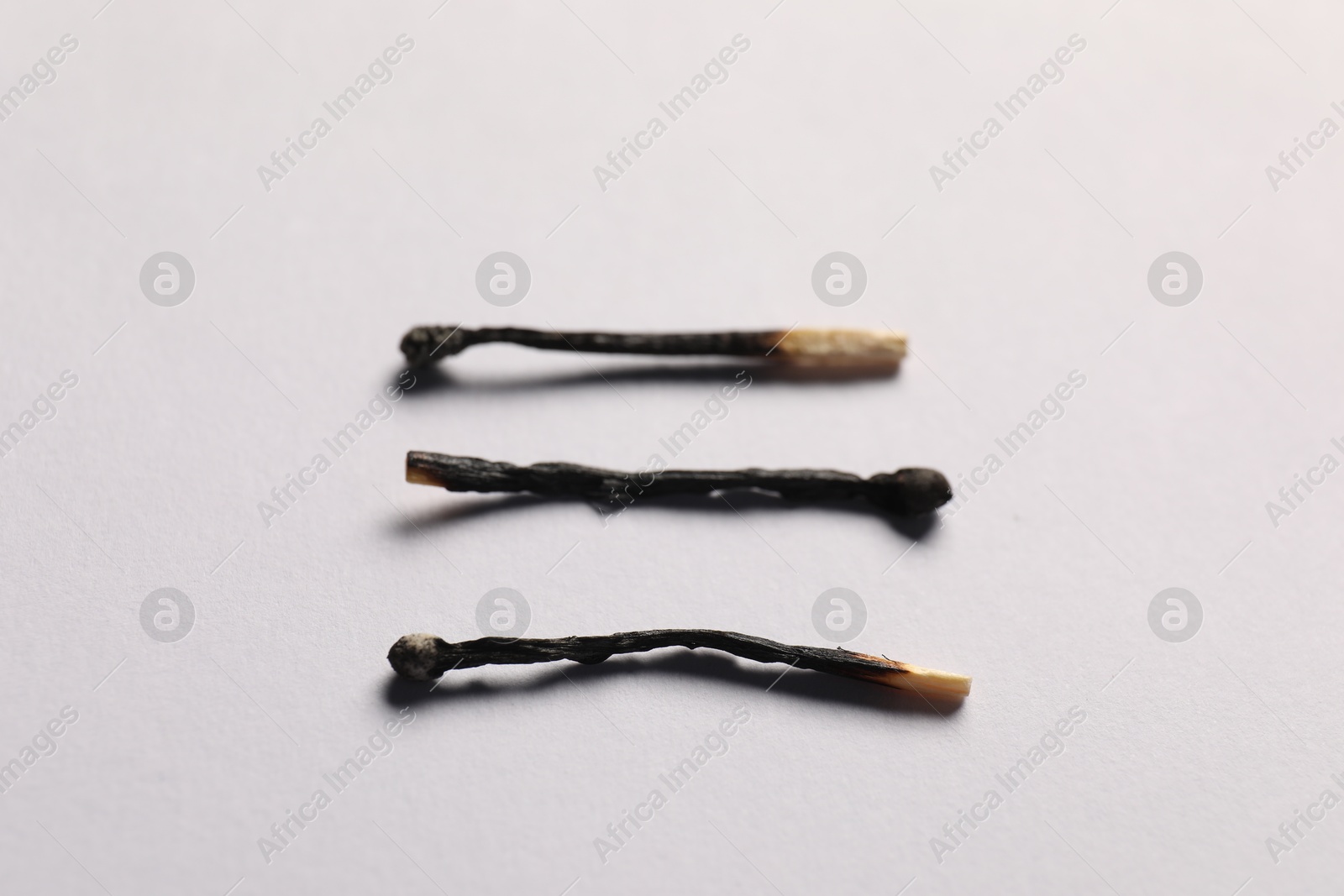 Burnt matches on grey background, closeup view Photo of Burnt matches on grey background, closeup view