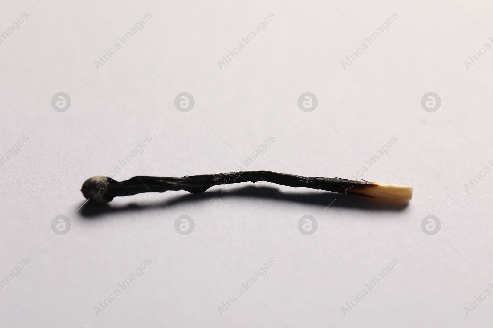 One burnt match on grey background, closeup view Photo of One burnt match on grey background, closeup view