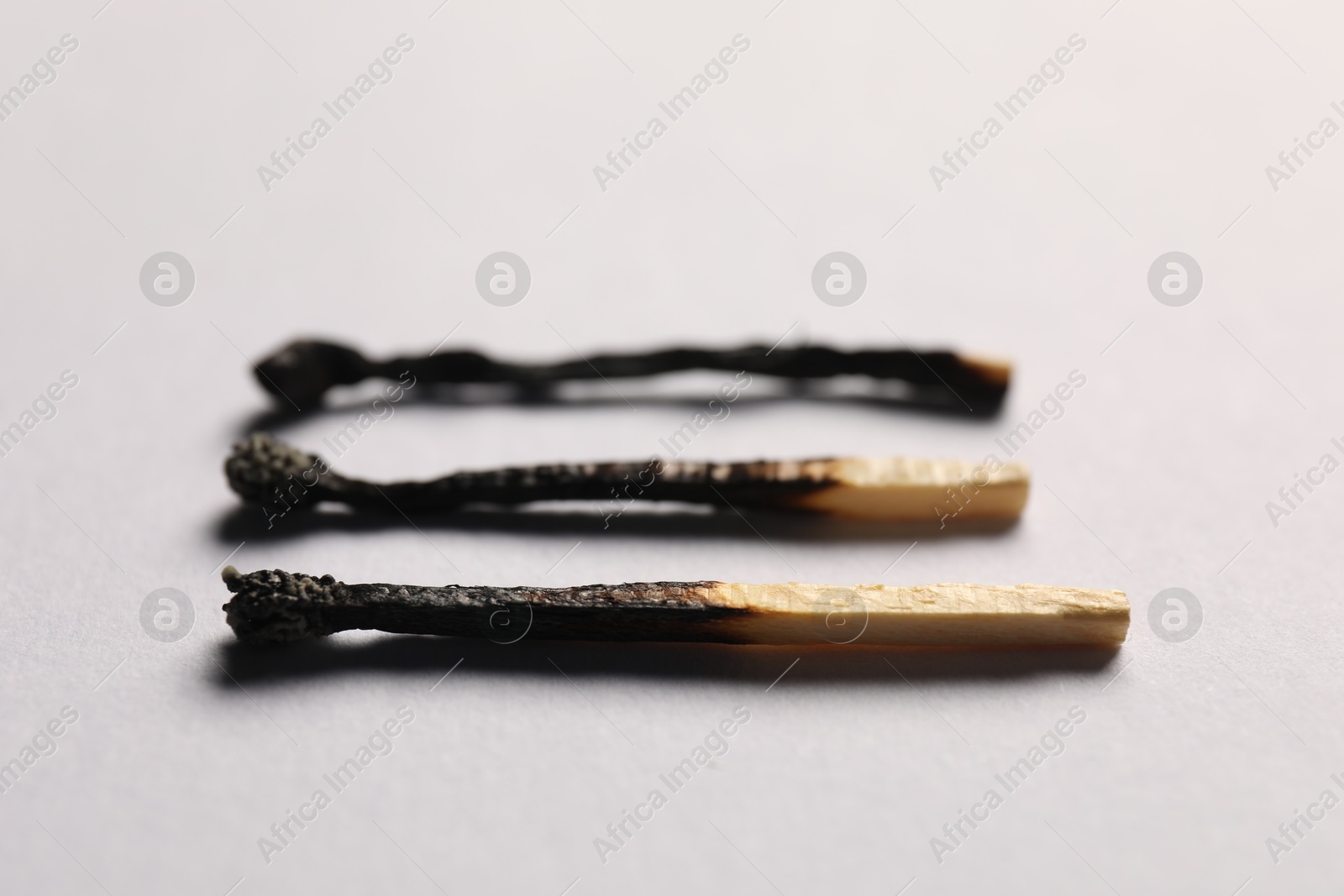 Burnt matches on grey background, closeup view Photo of Burnt matches on grey background, closeup view