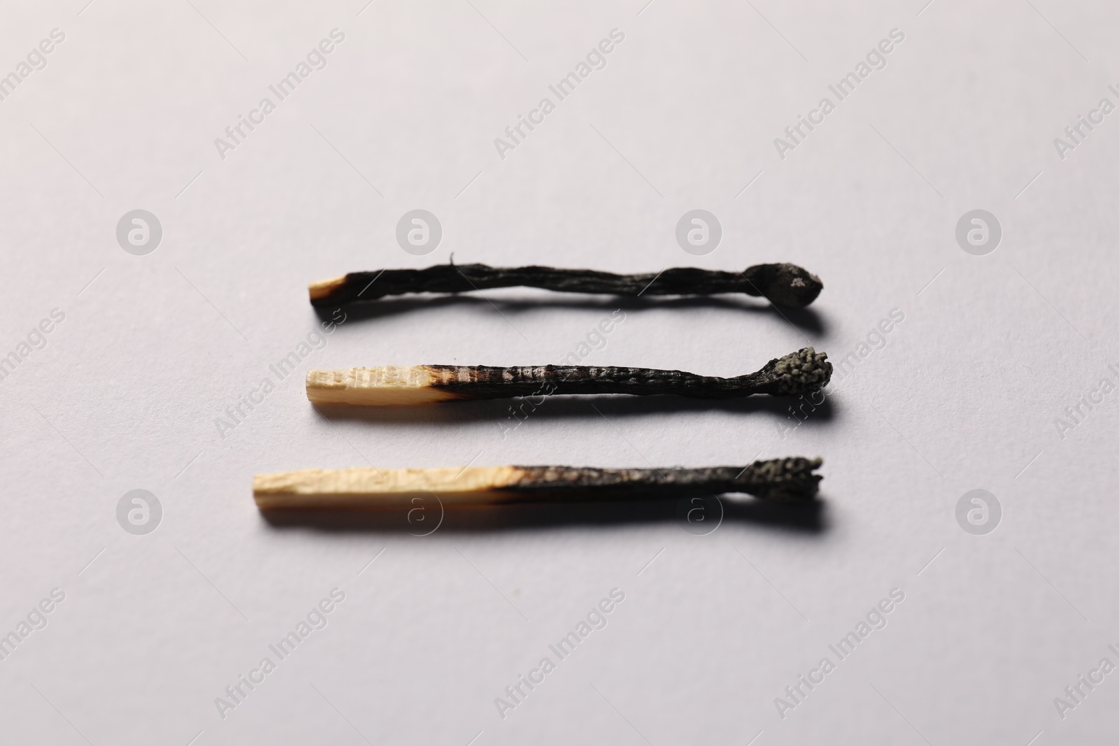 Burnt matches on grey background, closeup view Photo of Burnt matches on grey background, closeup view