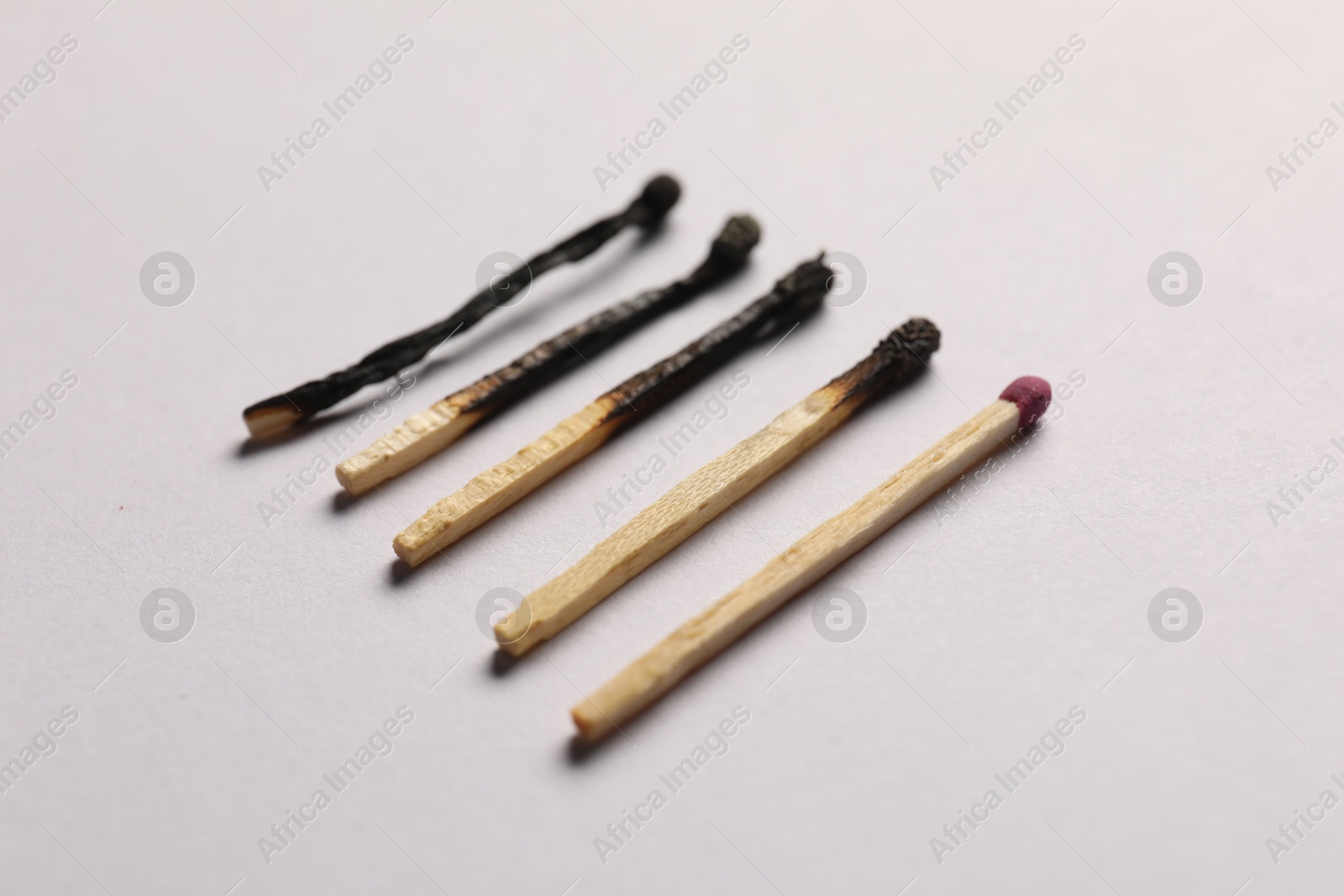 Burnt and whole matches on grey background, closeup Photo of Burnt and whole matches on grey background, closeup