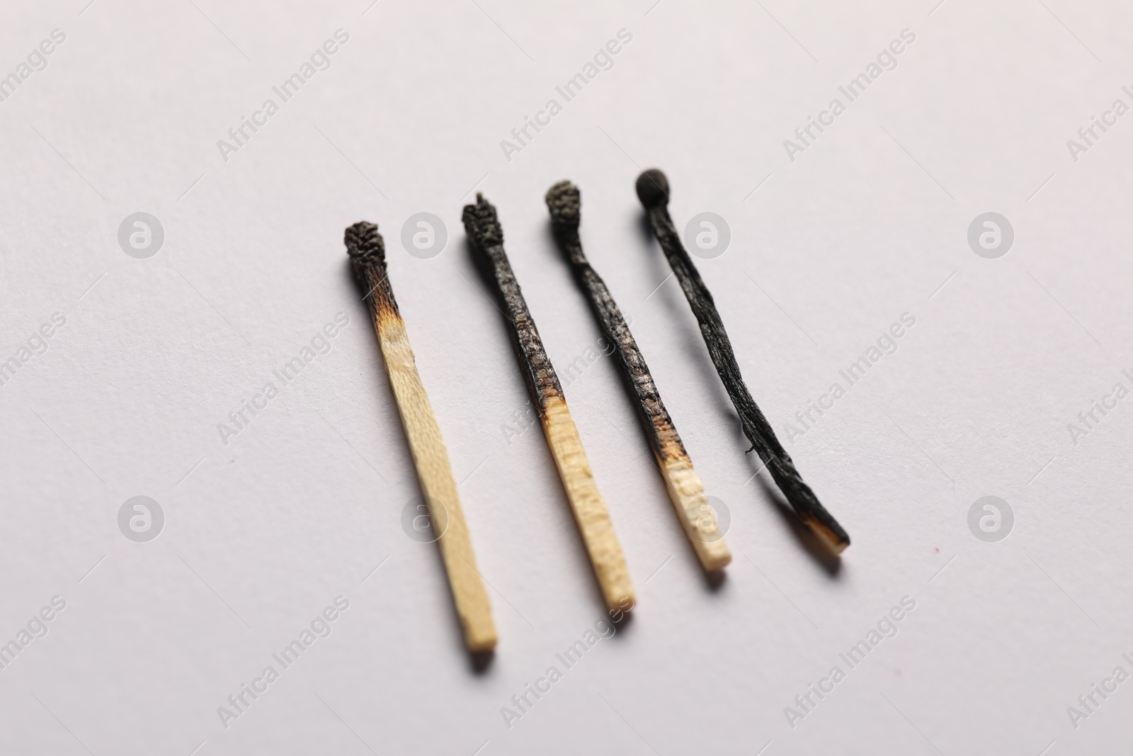 Burnt matches on grey background, closeup view Photo of Burnt matches on grey background, closeup view