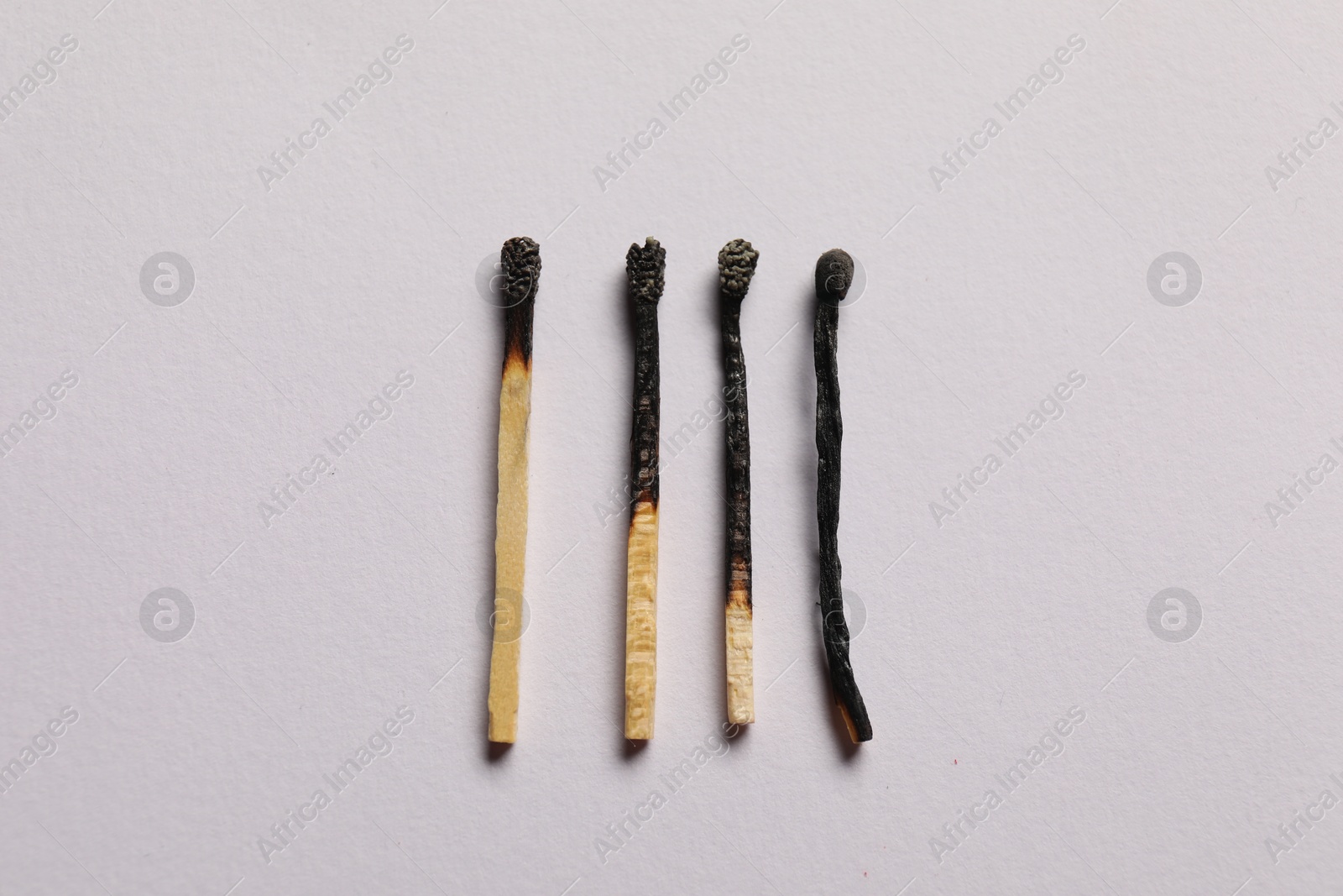 Burnt matches on grey background, flat lay Photo of Burnt matches on grey background, flat lay
