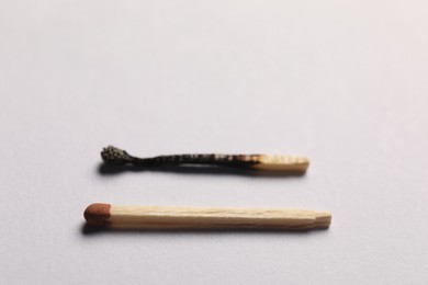 Photo of Burnt and whole matches on grey background, selective focus