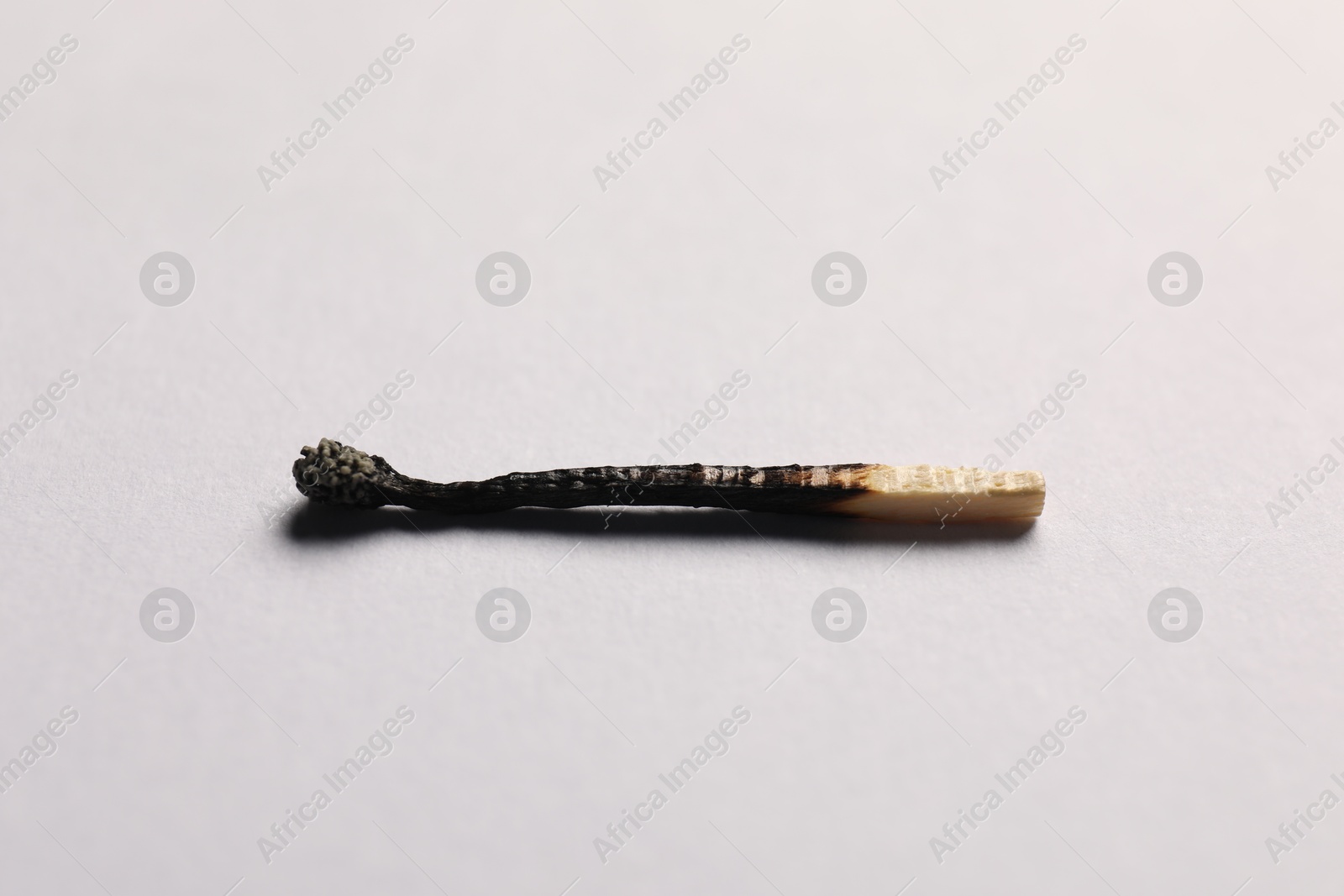One burnt match on grey background, closeup view Photo of One burnt match on grey background, closeup view
