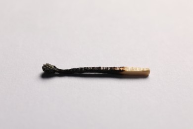 Photo of One burnt match on grey background, closeup view