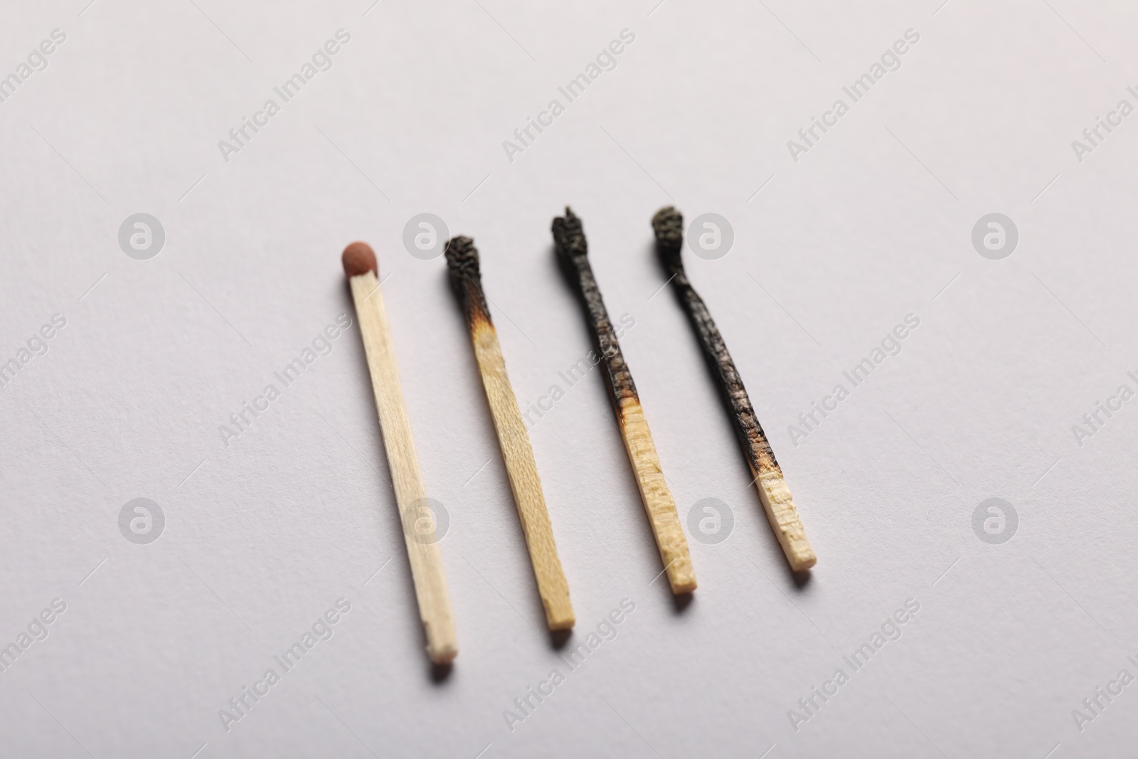Burnt and whole matches on grey background, closeup Photo of Burnt and whole matches on grey background, closeup