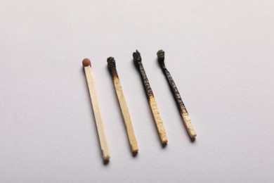 Photo of Burnt and whole matches on grey background, closeup