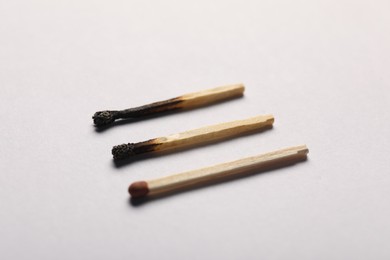 Photo of Burnt and whole matches on grey background, closeup