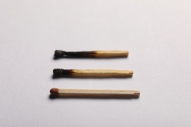 Photo of Burnt and whole matches on grey background, closeup