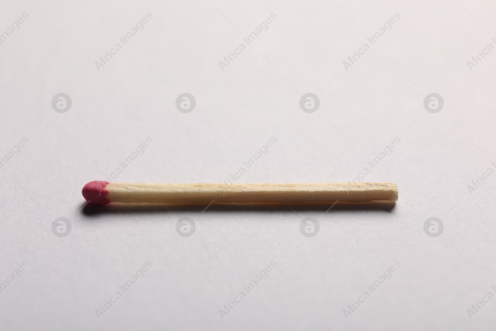 One match with pink head on grey background, closeup Photo of One match with pink head on grey background, closeup
