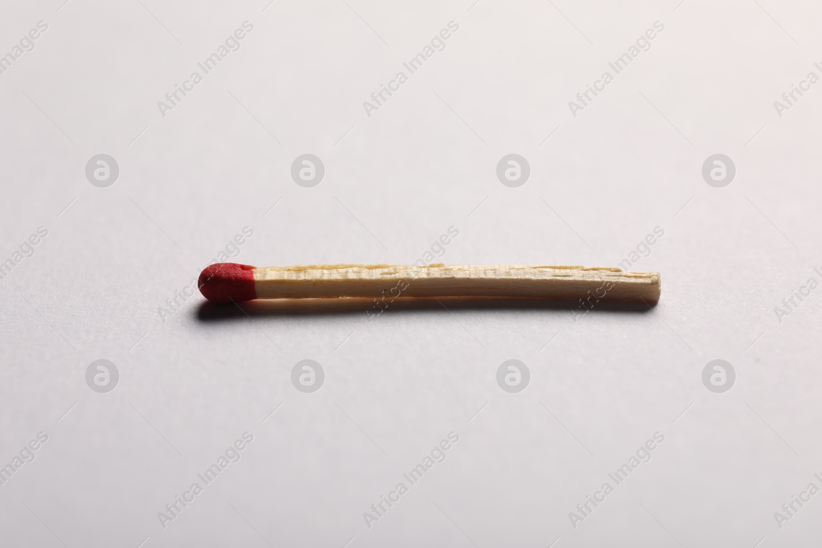 One match with red head on grey background, closeup Photo of One match with red head on grey background, closeup