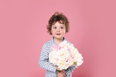Photo of Cute little boy with bouquet of beautiful peonies on pink background