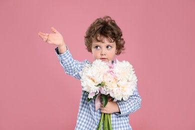 Photo of Cute little boy with bouquet of beautiful peonies on pink background