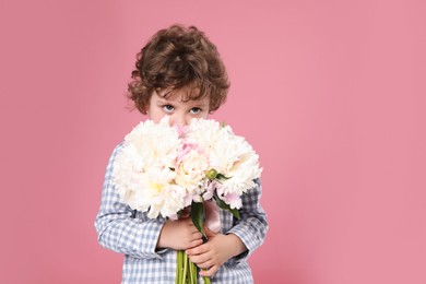 Photo of Cute little boy with bouquet of beautiful peonies on pink background. Space for text
