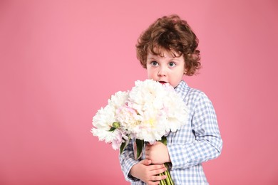 Photo of Cute little boy with bouquet of beautiful peonies on pink background. Space for text