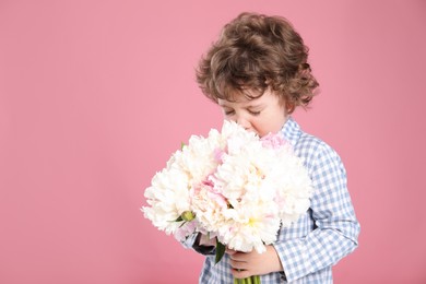 Photo of Cute little boy with bouquet of beautiful peonies on pink background. Space for text
