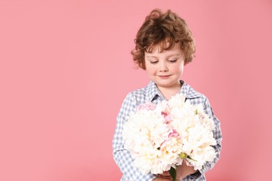 Photo of Cute little boy with bouquet of beautiful peonies on pink background. Space for text