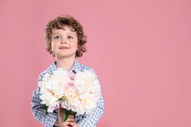 Photo of Cute little boy with bouquet of beautiful peonies on pink background. Space for text
