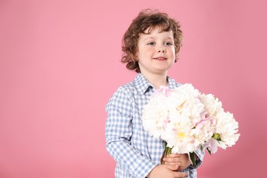 Photo of Cute little boy with bouquet of beautiful peonies on pink background. Space for text
