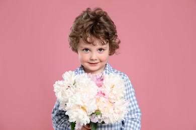 Photo of Cute little boy with bouquet of beautiful peonies on pink background