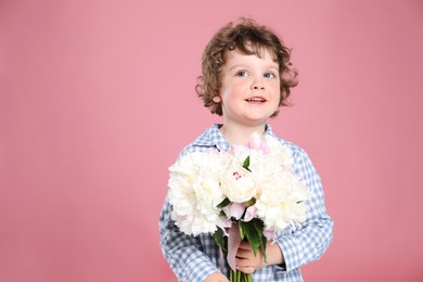 Photo of Cute little boy with bouquet of beautiful peonies on pink background. Space for text