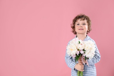Photo of Cute little boy with bouquet of beautiful peonies on pink background. Space for text