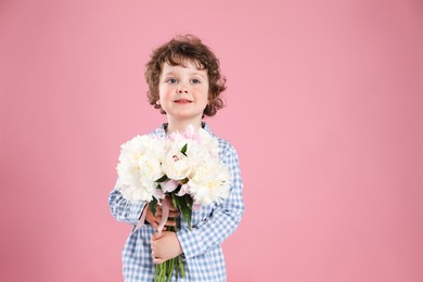 Photo of Cute little boy with bouquet of beautiful peonies on pink background. Space for text