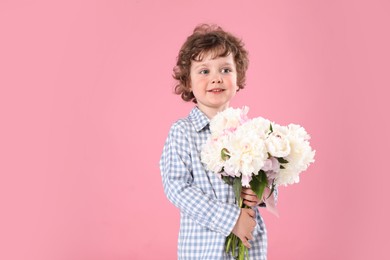 Photo of Cute little boy with bouquet of beautiful peonies on pink background. Space for text