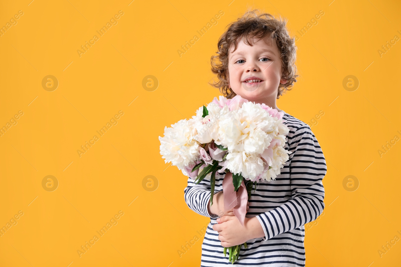 Cute little boy with bouquet of beautiful peonies on yellow background. Space for text Photo of Cute little boy with bouquet of beautiful peonies on yellow background. Space for text